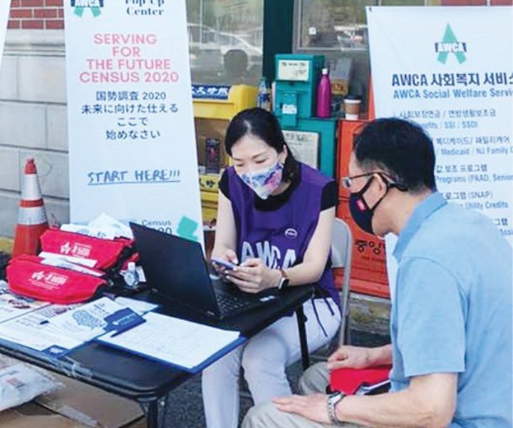A volunteer of Asian Women’s Christian Association assists a Korean to fill out Census online with a mobile kiosk device at Hanyang Mart in Ridgefield, NJ on July 30, 2020.