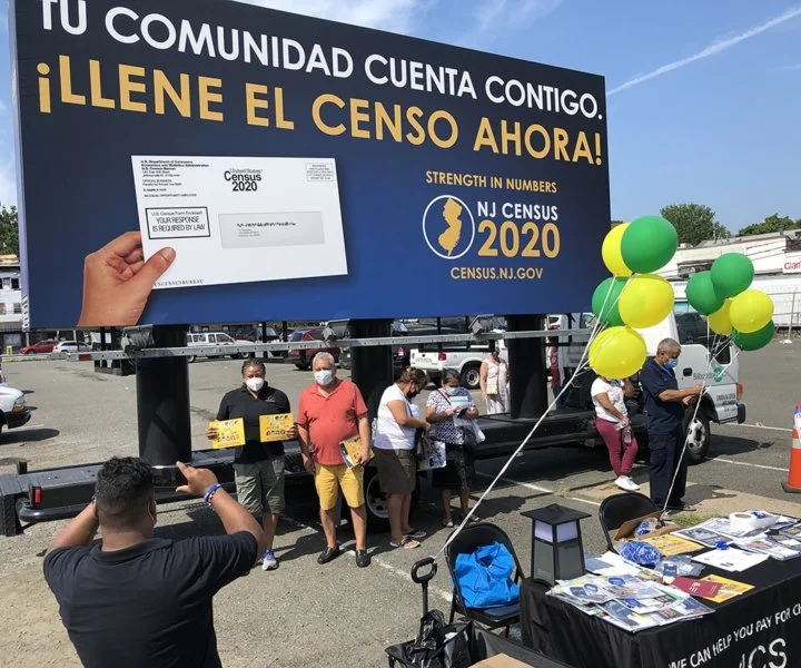 People stand for a photo in front of a billboard truck at a Census outreach event in Paterson, NJ.